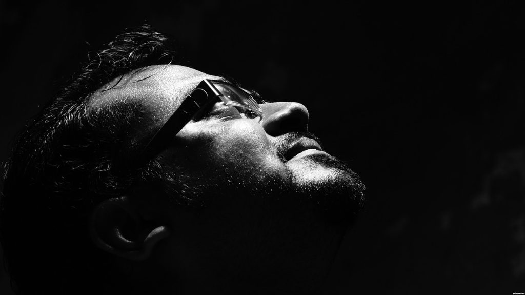 Zoomed in black and white photo of a man looking up and praying